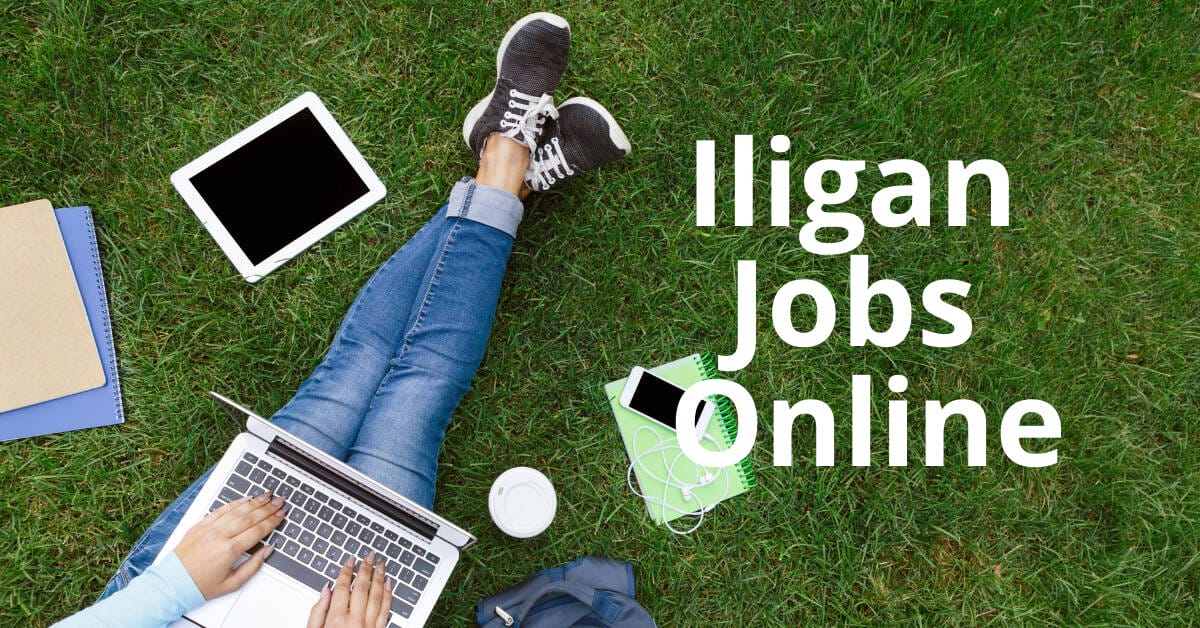 Person on grass using a laptop, with tablet, phone, and notebook nearby. Text: Iligan City Jobs Online.