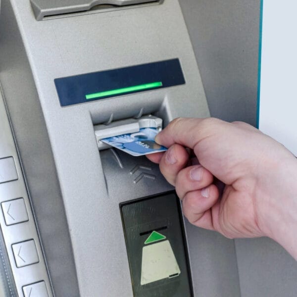 hand inserting a card into an iligan atm, with buttons and a green light indicator above the card slot.