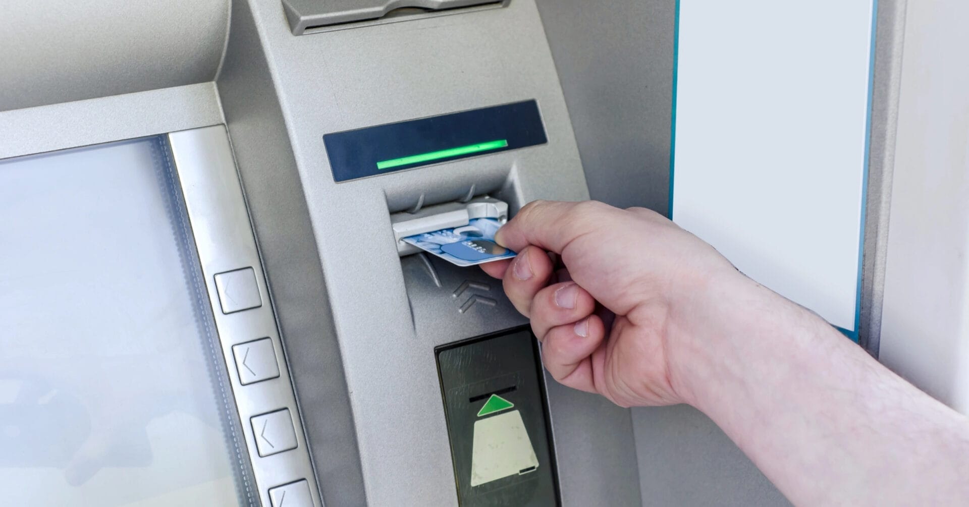 hand inserting a card into an iligan atm, with buttons and a green light indicator above the card slot.